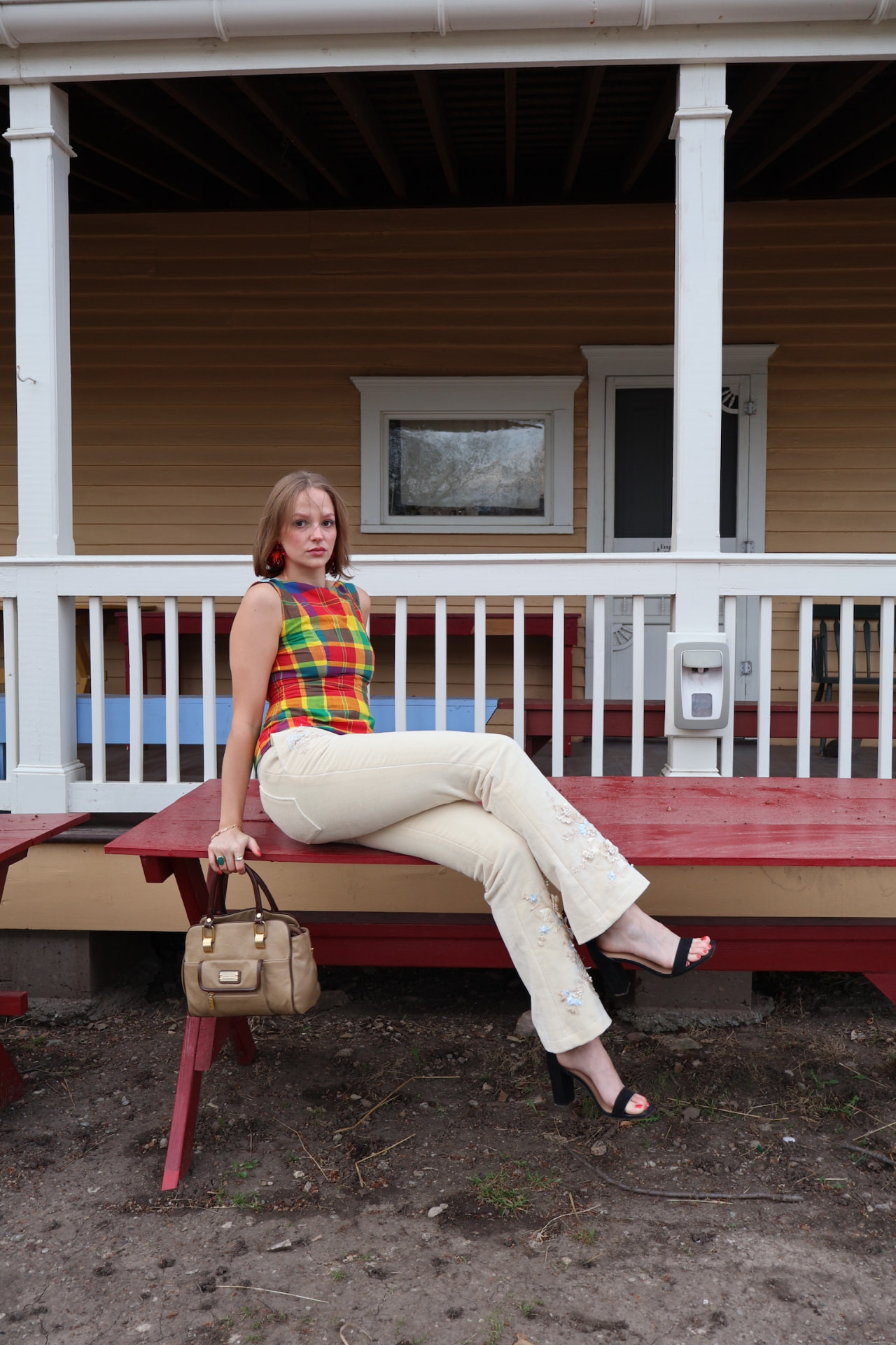 Model seated in a Range & Reverie plaid top and embellished white trousers