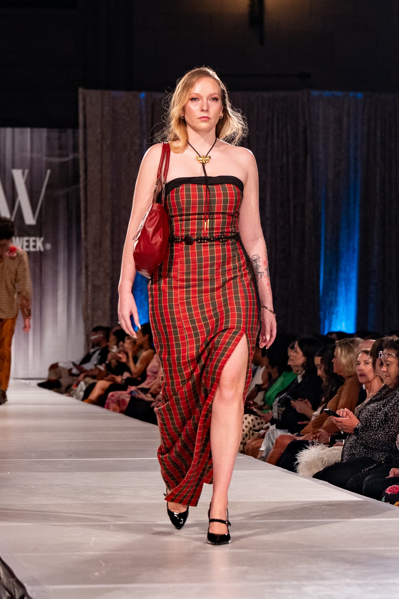 Model walking the Kansas City Fashion Week runway in a red plaid Range & Reverie dress