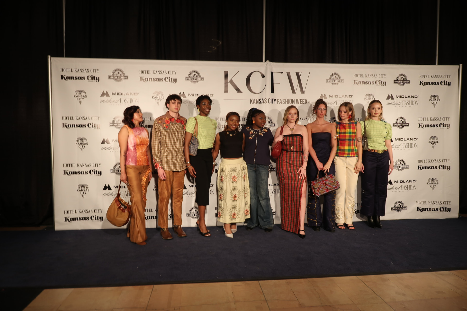 Raine Cox with the models wearing Range & Reverie at the Kansas City Fashion Week backdrop