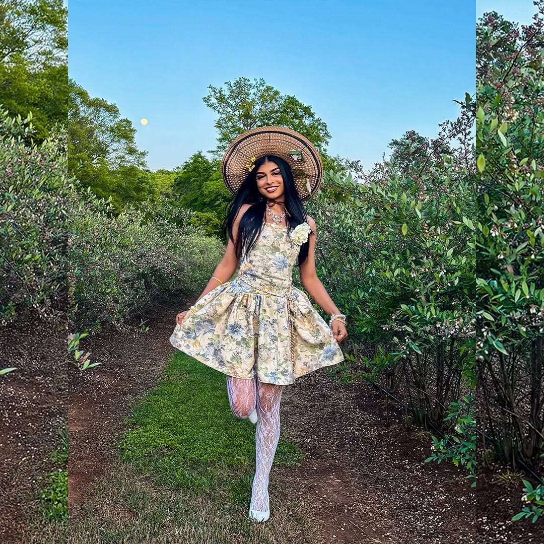 Model Taz in a floral dress, wide-brimmed hat, and lace boots in a garden